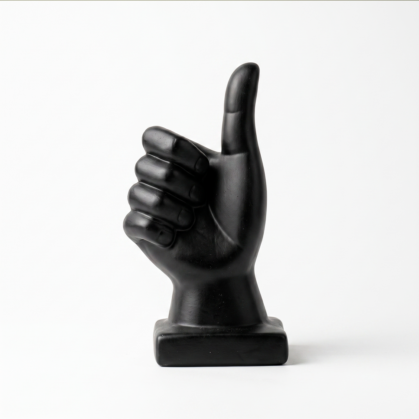 Escultura de mano pulgar arriba en cerámica negra mate, vista sobre fondo blanco