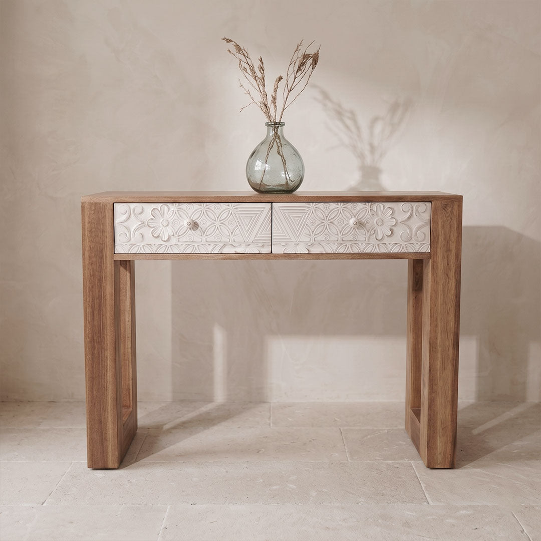Consola en roble macizo con cajones tallados en blanco y jarrón decorativo, vista frontal