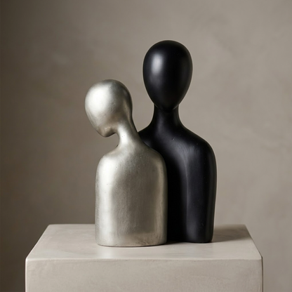 Set de dos esculturas abstractas de pareja en resina, una negra mate y otra en acabado plateado, sobre fondo blanco