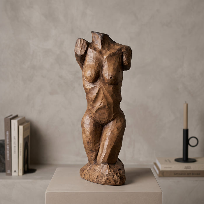 Escultura de torso femenino en resina con acabado tipo talla en madera, sobre pedestal en ambiente — Loft Mobiliario