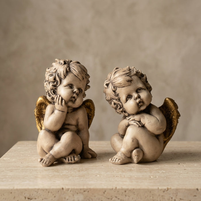 Set de dos angelitos querubines en resina con alas doradas, sentados en poses distintas, vista de producto — Loft Mobiliario