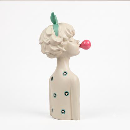 Figura decorativa niña con lazo agua marina y globo de chicle en resina blanca, sobre base de piedra travertino en ambiente neutro
