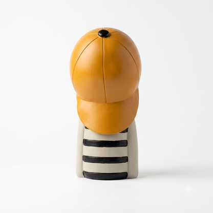 Figura decorativa niño con gorra mostaza, vista posterior que muestra la gorra, resina marfil, fondo blanco