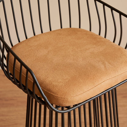 Silla de barra en varilla metálica negra con asiento coñac, vista frontal sobre piso de madera