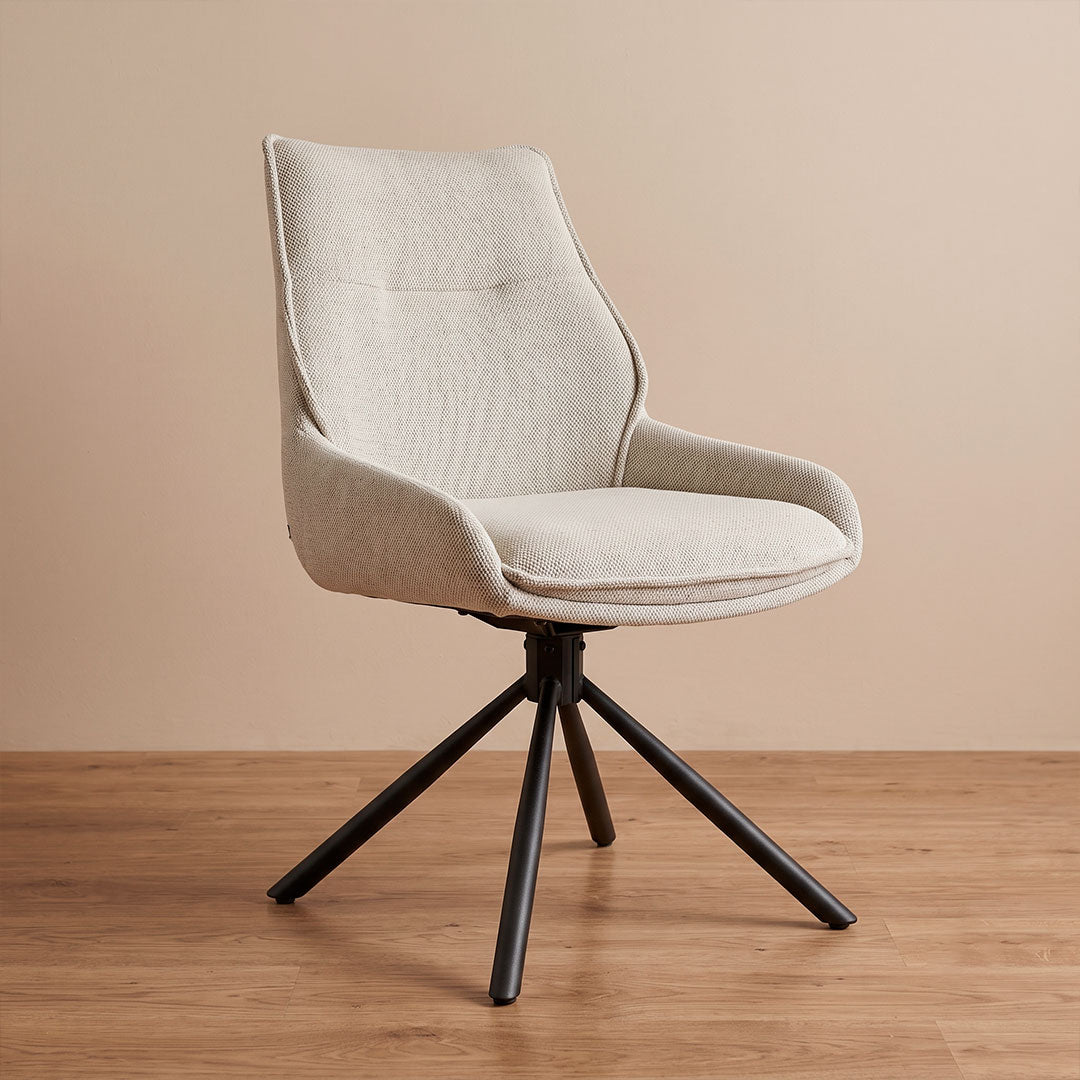 Silla de comedor giratoria en lino beige con base metálica negra, vista diagonal en ambiente cálido