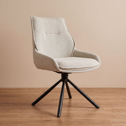 Silla de comedor giratoria en lino beige con base metálica negra, vista diagonal en ambiente cálido