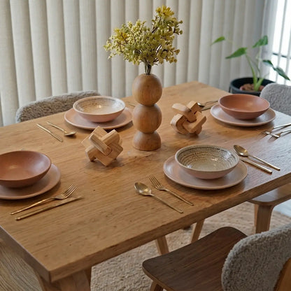 Detalle de mesa de comedor en madera natural con decoración de vajilla