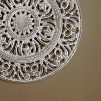Primer plano del relieve y acabado artesanal de mandala de madera tallada para decoración de interiores.
