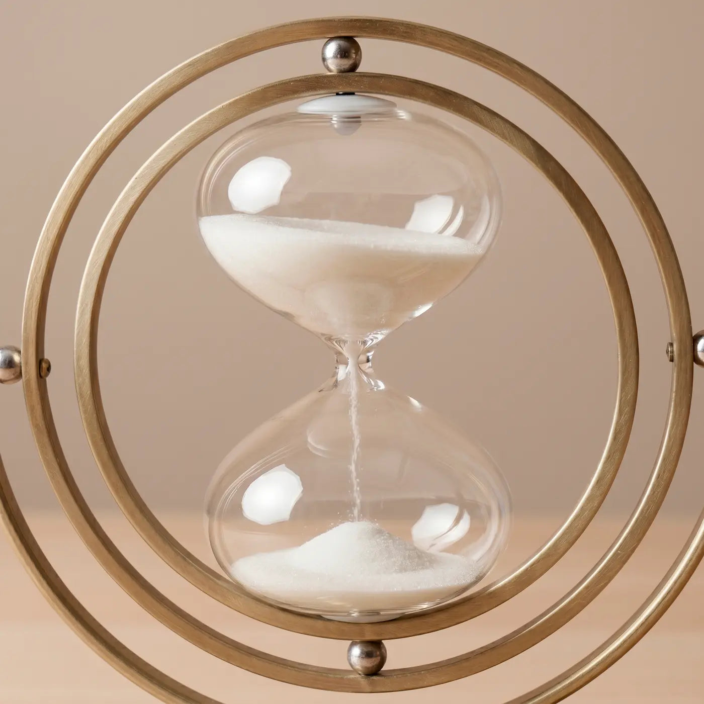 Reloj de arena decorativo en vidrio y estructura dorada para oficina moderna.